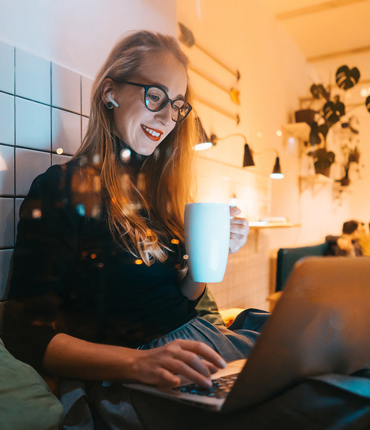 A woman writing emails on a laptop in a warm, plant-filled studio